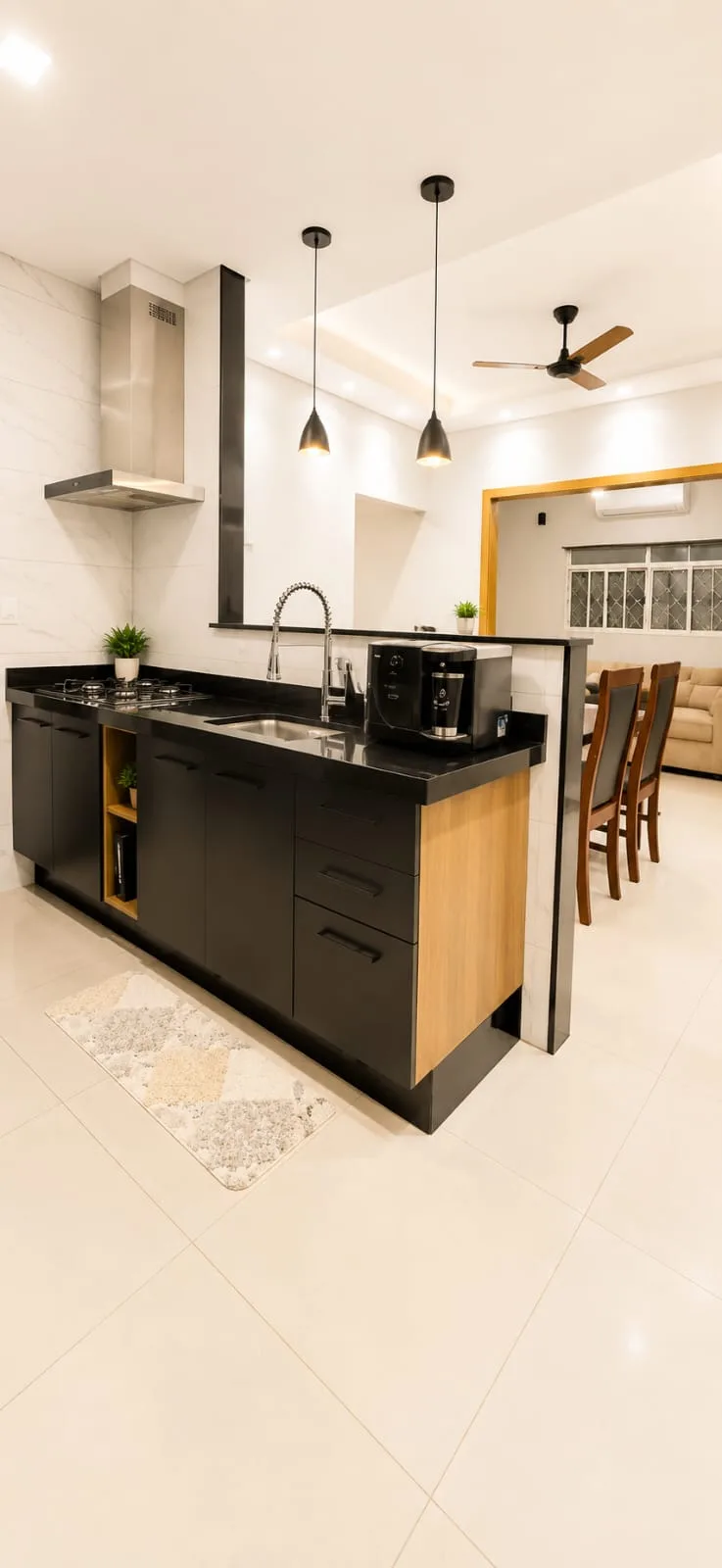 Cozinha com armários planejados, bancada, cooktop e coifa; copa ao fundo.