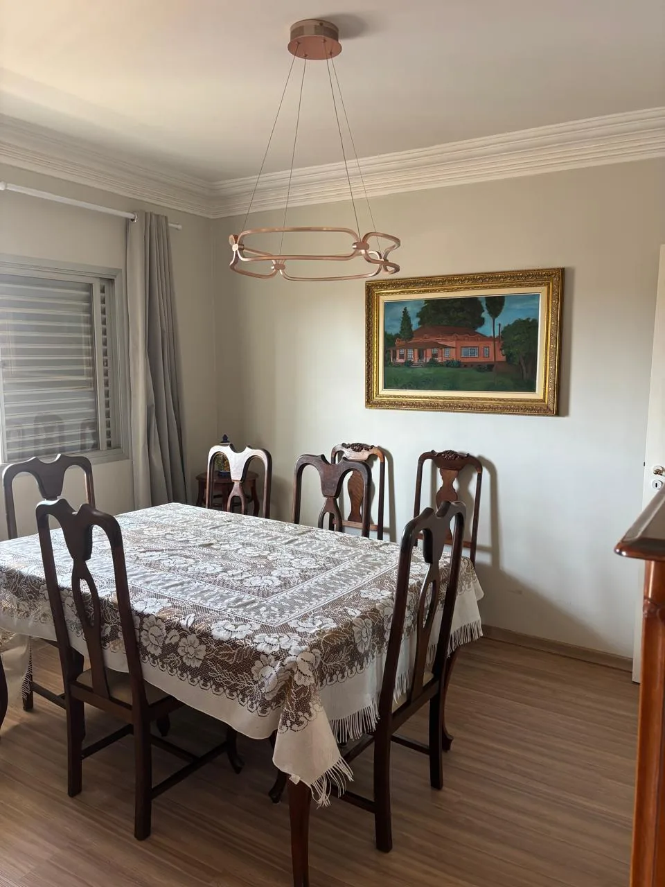 Sala de jantar com mesa, cadeiras, pendente e janela; mobiliário fotografado.